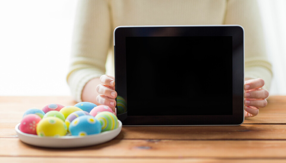 kvinne holder liten laptop ved siden av en tallerken med malte påskeegg