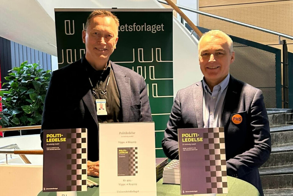 Rune Glomseth og Tor Håvard Bentzen bak et bord med boka 'Politiledelse – En helhetlig modell' utstilt