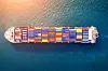 Aerial view of a container ship with colorful cargo containers sailing in dark blue water.