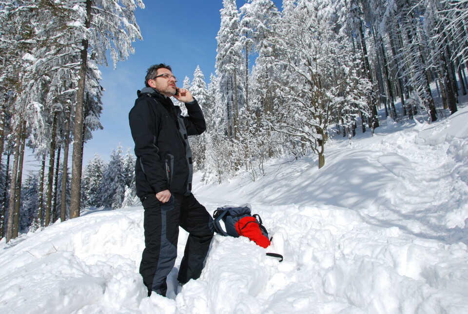 Mann på tur i snøen prater i telefon